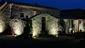 A stone building with a tiled roof, a small entrance, and potted plants. - Renovated Tuscan-style country house (Castel del Piano)
