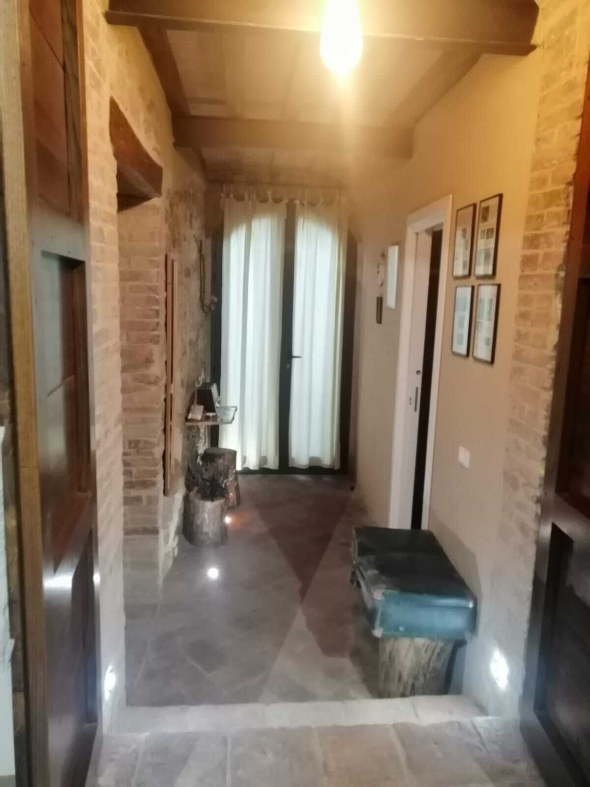 A hallway with stone walls, a wooden bench, and a door leading to a room.