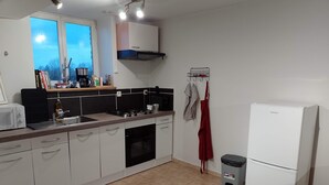 A modern kitchen with white cabinets, a gas stove, a microwave, and a white refrigerator. - Apartment with garden 30min from Lille! (Vieux-Berquin)