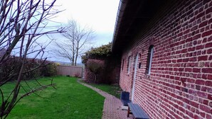 A brick building with a paved walkway and a bench. - Apartment with garden 30min from Lille! (Vieux-Berquin)