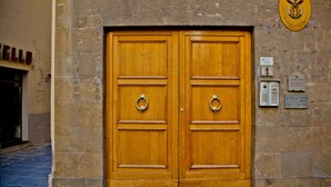 A wooden double door with a brass knocker, set in a stone wall with a plaque above.