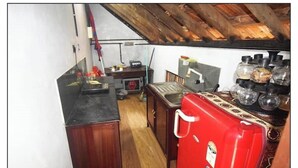 A compact kitchen with wooden cabinets, a red refrigerator, and a sink.