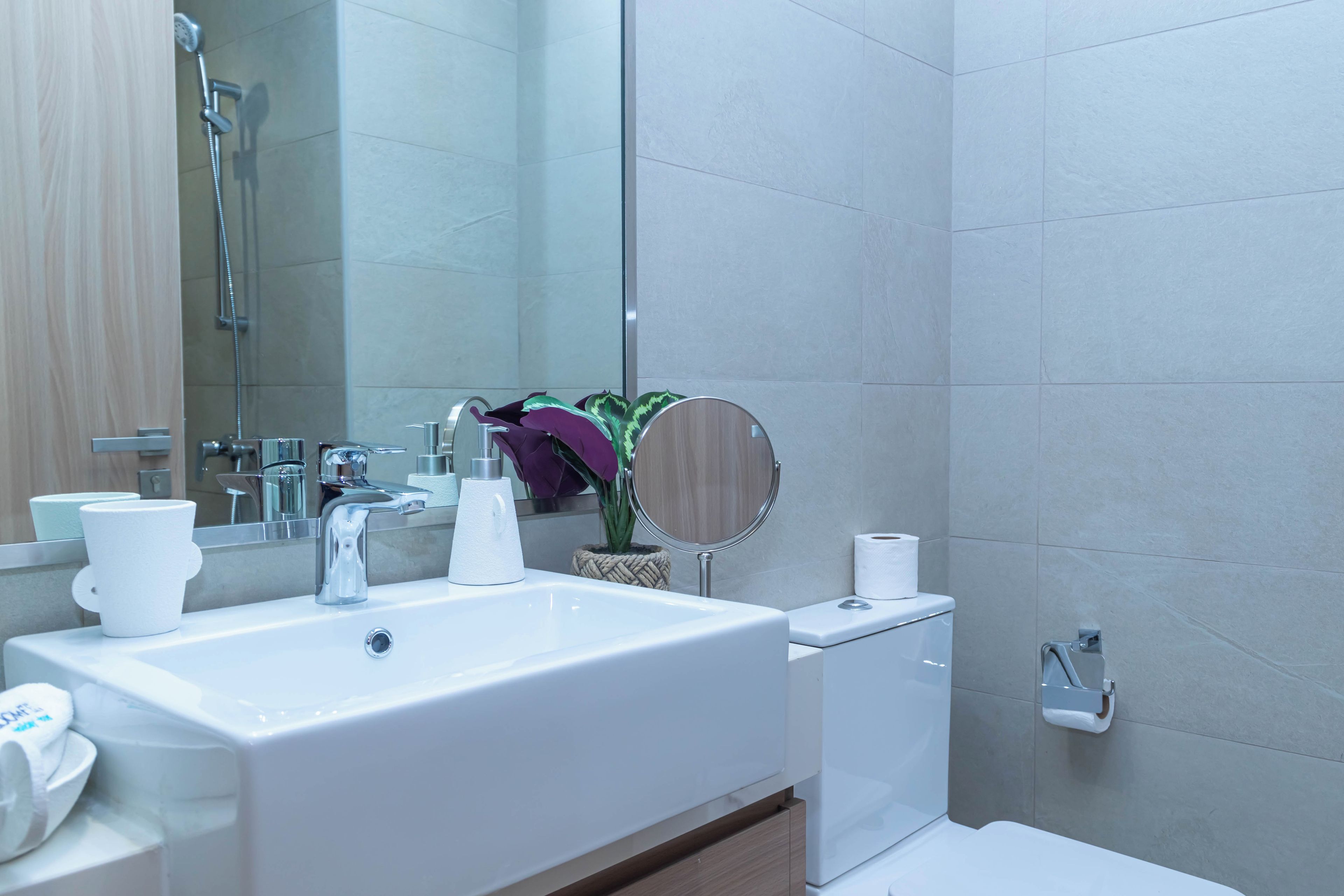 Een moderne badkamer met een groot wit wastafel, een spiegel, een toilet en een douche.