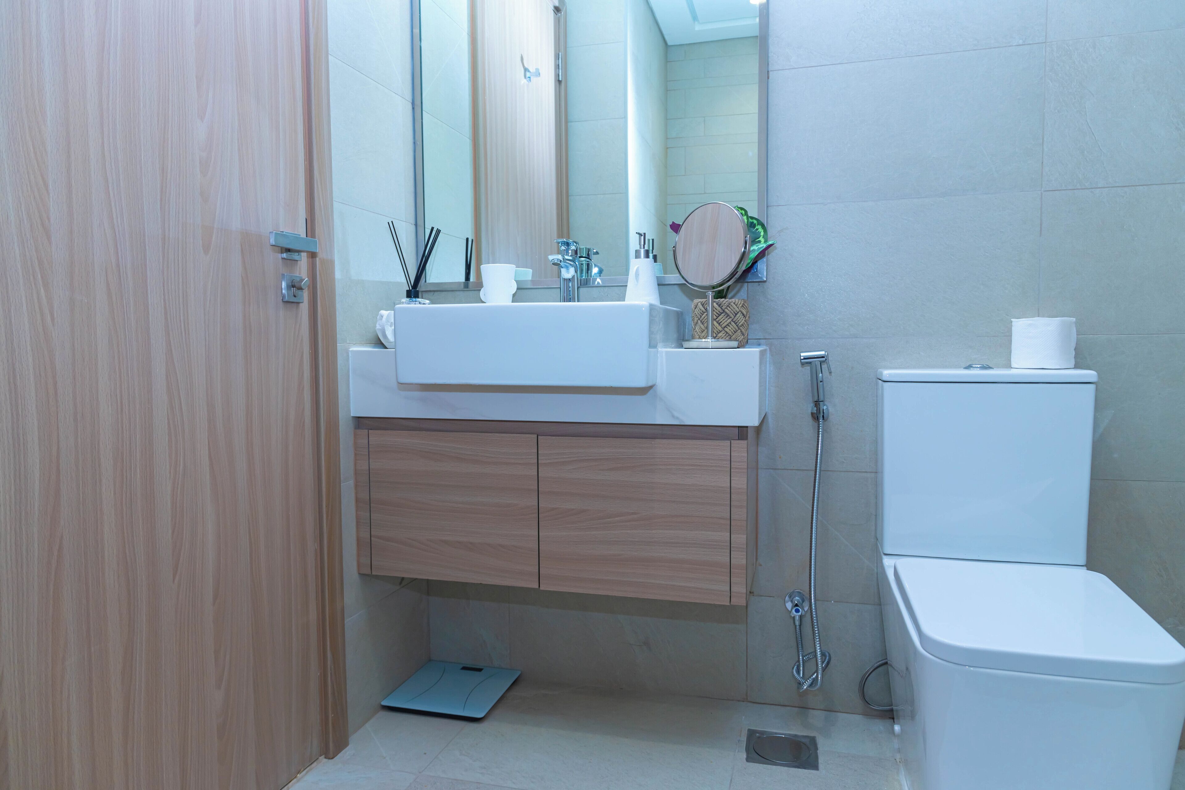 A modern bathroom with a wooden vanity, a white sink, a mirror, and a toilet.