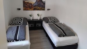 A bedroom with two single beds, a nightstand, and a wall-mounted painting. - Cozy bungalow for 4 people in the beautiful Hunsrück (Morbach)