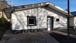 A modern building with a white exterior and black trim, featuring two windows and a door. - Cozy bungalow for 4 people in the beautiful Hunsrück (Morbach)