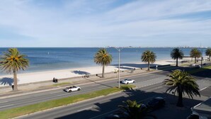 Eine Küstenstraße mit Palmen, einem Strand und wolkenlosem Himmel.