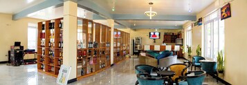 Un vestíbulo de hotel con zona de bar, asientos y una pantalla de televisión.