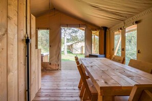 A wooden interior with a large table and benches, a tent-like roof, and a view of the outdoors. - Comet Glamping Tent, Ardennes (Signy-l’Abbaye)