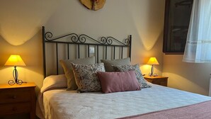 Un lit bien fait, recouvert d’une couvre-lit à motifs et agrémenté de plusieurs coussins, avec deux tables de chevet de chaque côté, sur lesquelles sont posées des lampes.