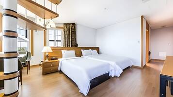 Moderni hotellihuone, jossa on suuri sänky, puulattia ja suuret ikkunat, joista on näkymä ulos.
