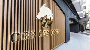 Une façade d’immeuble avec des lambris en bois verticaux et une grande enseigne dorée portant le numéro « 033 655 0078 ».
