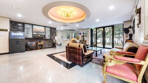 Un hall d’hôtel moderne doté d’un comptoir d’accueil, d’un espace salon et de grandes fenêtres offrant une vue sur l’extérieur.