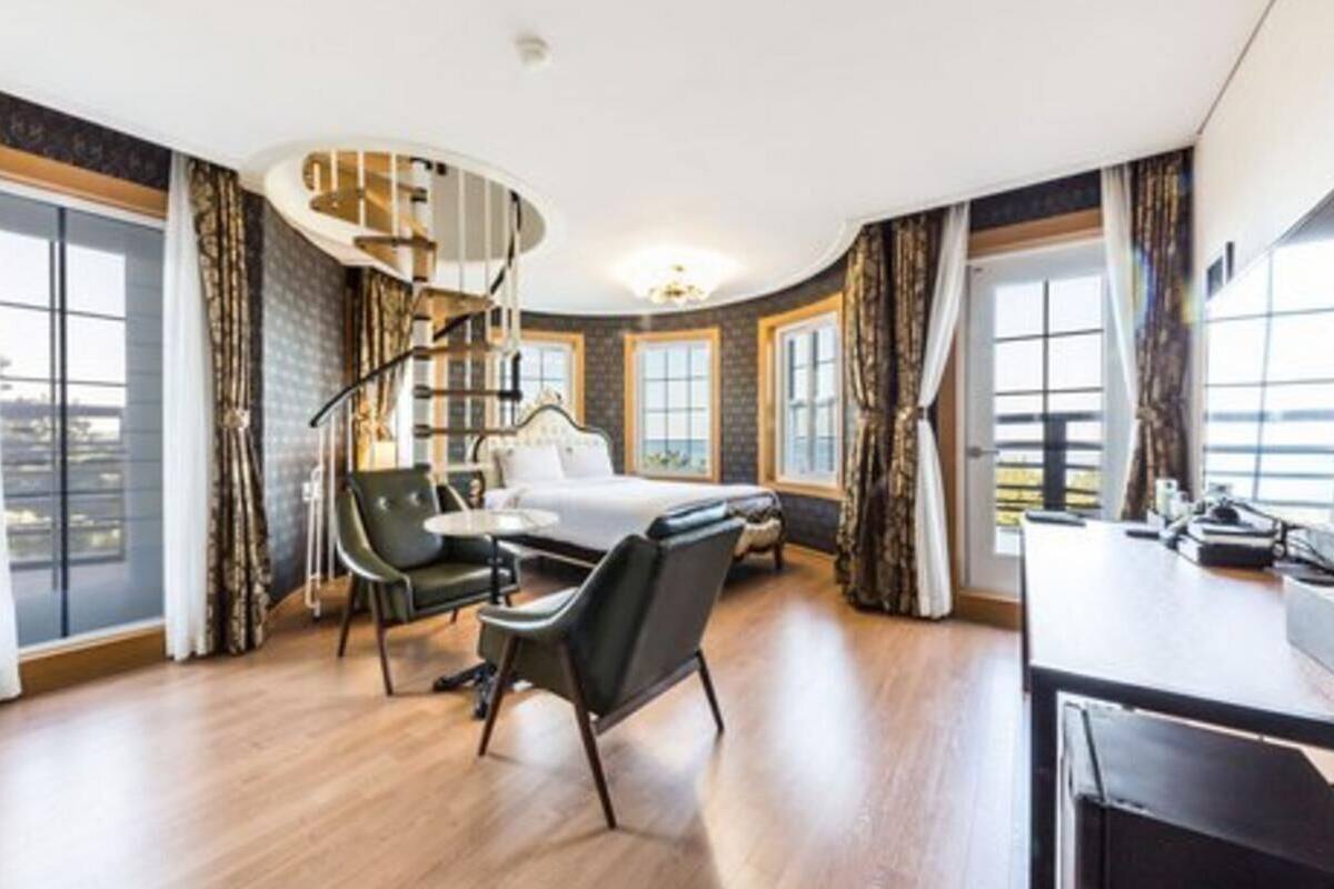 Una habitación de hotel moderna con una escalera de caracol, una cama, un escritorio y vistas a la ciudad.