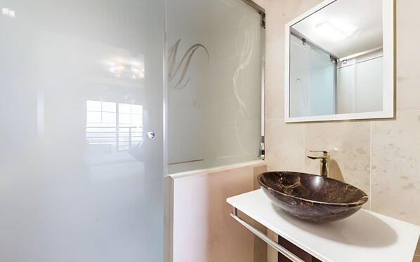 A bathroom with a white sink, a mirror, and a shower.