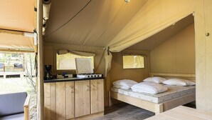 A tented room with a bed, a small kitchenette, and a wooden table. - Terrace Apartment with Forest (Dochamps)