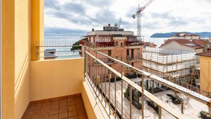 Un balcon donnant sur un chantier de construction, une grue et une étendue d’eau.