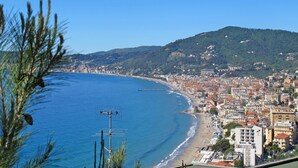 Un paysage urbain côtier avec une plage, des bâtiments et une colline en arrière-plan.