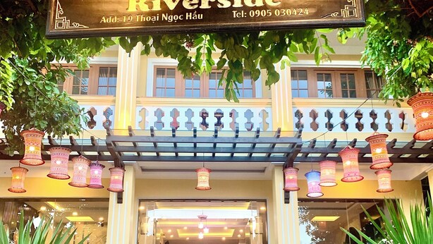 A hotel entrance with a sign reading "AMAN Riverside" and a contact number. - Aman Riverside Hotel (Da Nang)