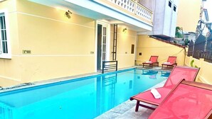 A swimming pool with red lounge chairs and a glass balustrade. - Aman Riverside Hotel (Da Nang)
