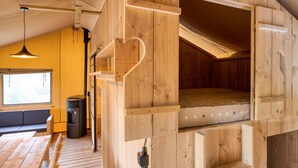 A wooden interior with a loft bed, a sofa, and a heater.