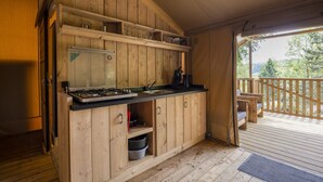 A wooden kitchen with a gas stove, sink, and shelves above.