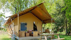 Une cabane en bois rustique dotée d’un porche abrité, d’un vélo et d’une table de pique-nique.