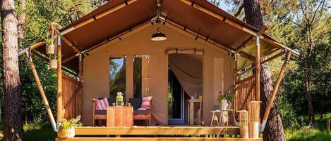 A wooden cabin with a covered porch, a small table, and a chair.
