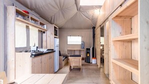 Een kleine keuken met houten kastjes, een fornuis en een eethoek.