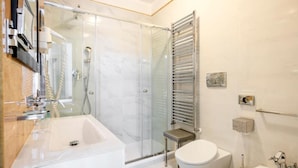 A modern bathroom with a glass shower enclosure, a white sink, a toilet, and a bidet. - The Five Oscars Inn (Rome)