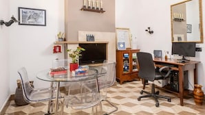 A modern office with a glass table, clear chairs, a wooden desk with a computer, and a fireplace with awards. - The Five Oscars Inn (Rome)