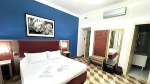 A hotel room with a large bed, a headboard, a bedside table, a mirror, a wardrobe, and a bathroom visible through an open door. - The Five Oscars Inn (Rome)