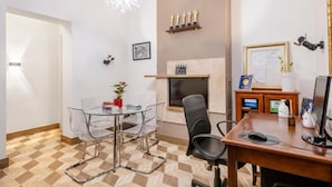 A modern office with a glass table, clear chairs, a wooden desk, a computer, and a fireplace with trophies. - The Five Oscars Inn (Rome)
