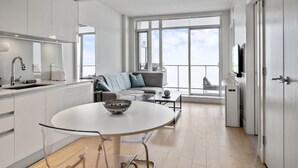 A modern apartment with a kitchen, dining area, and living room. - DT Views | AC | Pullout Couch | Mins to Saddledome (Calgary)