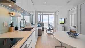 A modern kitchen with a built-in stove, a dining area with a round table, and a large window offering a view. - DT Views | AC | Pullout Couch | Mins to Saddledome (Calgary)