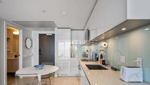 A modern kitchen with a white countertop, stainless steel appliances, and a glass backsplash. - DT Views | AC | Pullout Couch | Mins to Saddledome (Calgary)