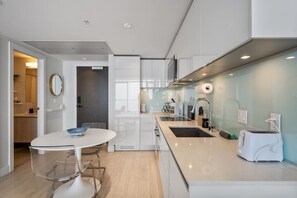 Una cucina moderna con piano di lavoro bianco, elettrodomestici in acciaio inossidabile e schienale in vetro.