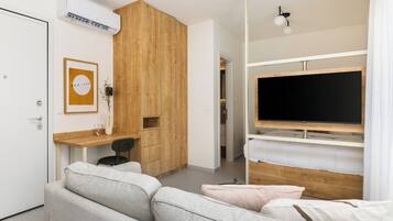 A modern bedroom with a TV, bunk beds, a desk, and a sofa.