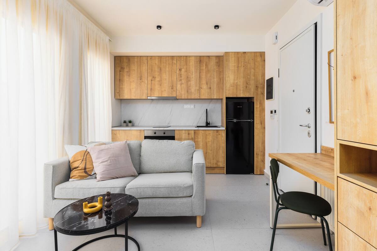 A modern living room with a grey sofa, a small black table, and a wooden dining table.