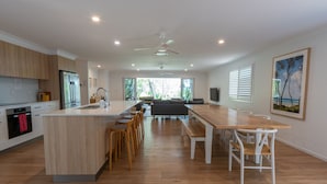 Une cuisine moderne dotée d’un îlot central, de planchers en bois et d’un coin repas avec une longue table et des chaises.
