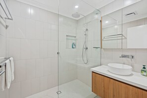 Une salle de bain moderne avec une douche à parois de verre, un lavabo blanc et un meuble en bois.