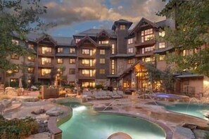 A multi-story hotel with a pool area featuring a hot tub and a small waterfall. - Studio-Peak 7 Resort, Hot Tub, Pool, Ski/In/Out! (Breckenridge)