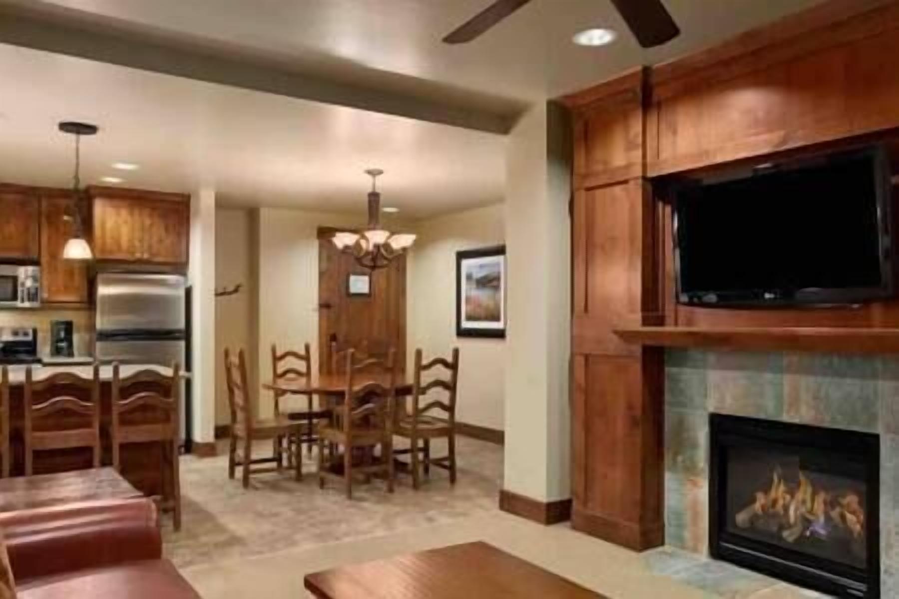 A spacious living room with a fireplace, wooden dining table, and chairs.