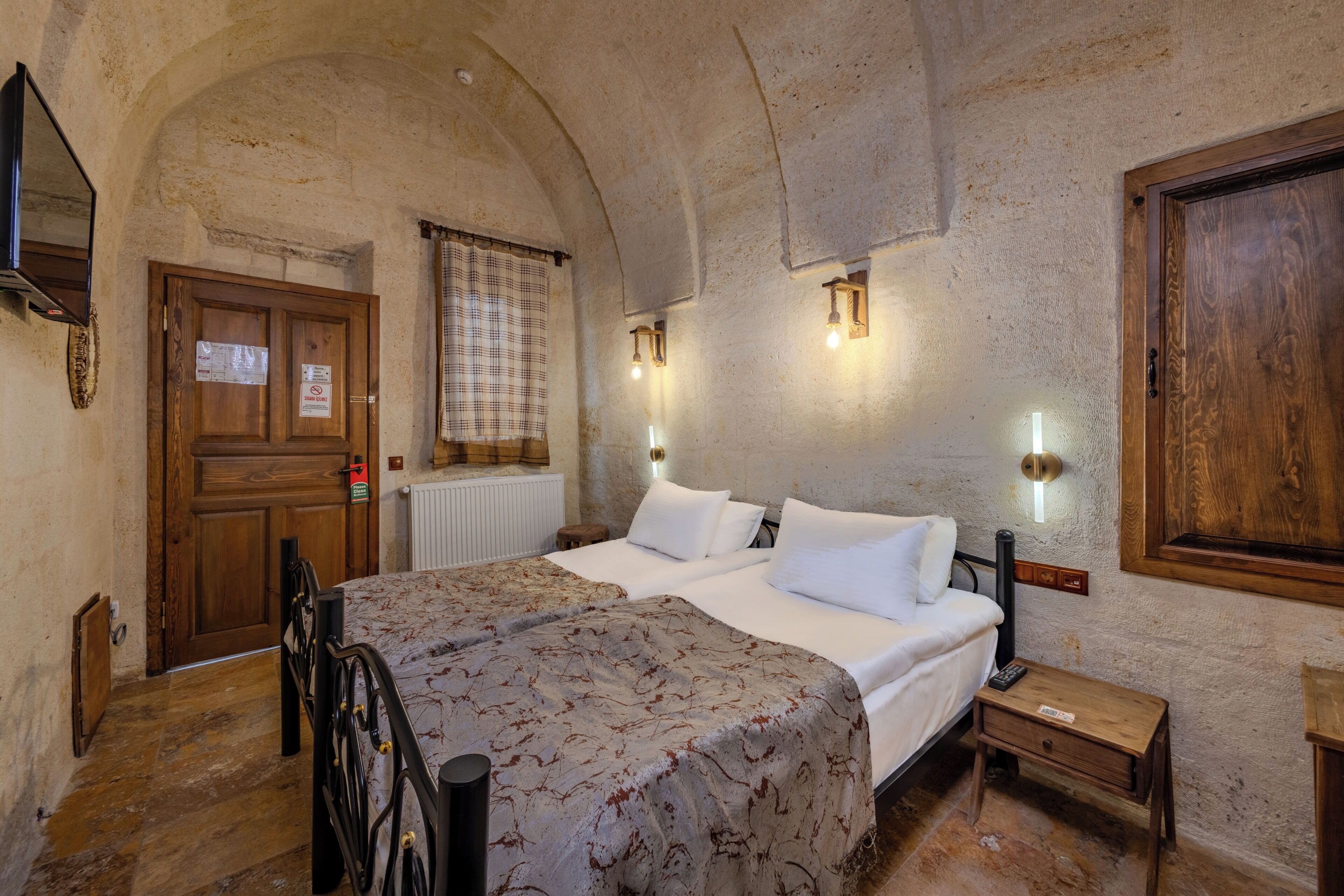 Una habitación con cama, puerta de madera, radiador y una mesita de noche.