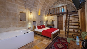 Una habitación con una cama, una escalera de madera, una silla de madera, una mesita pequeña y una bañera grande.