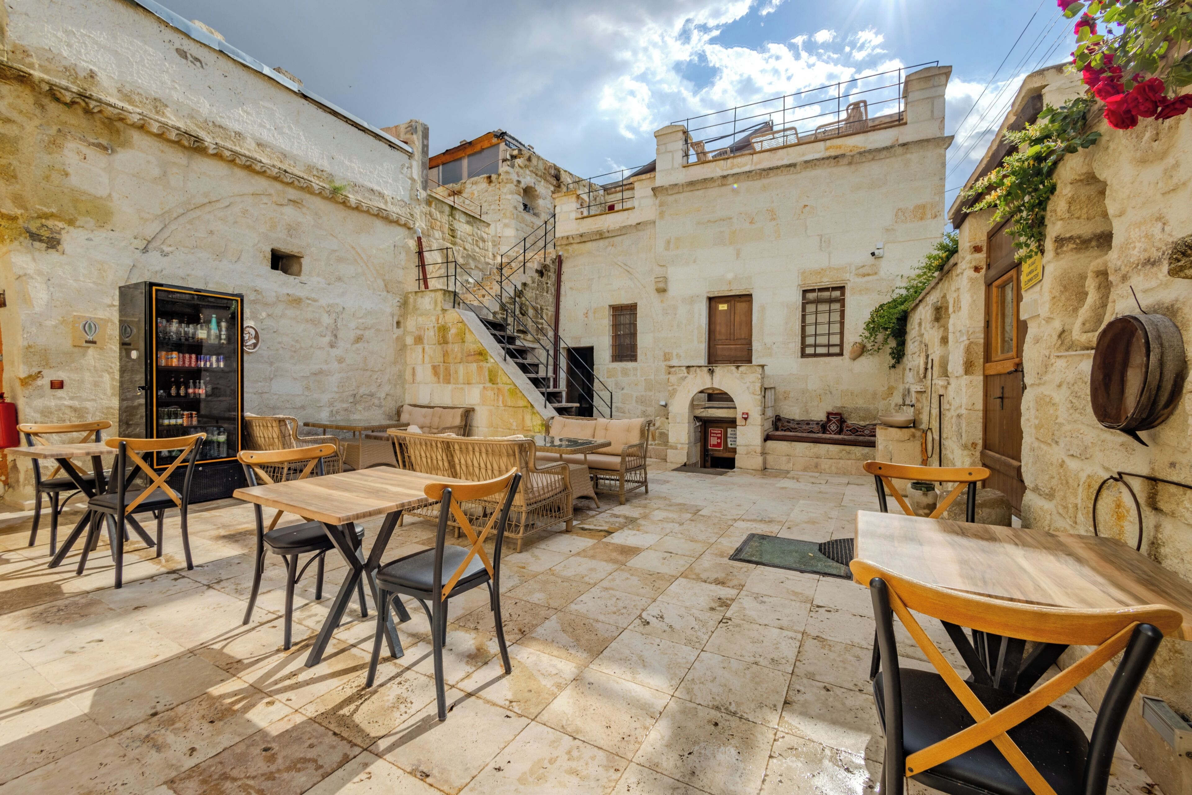 Un patio con paredes de piedra, asientos al aire libre, una escalera y una zona de bar.