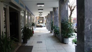 A hotel corridor with a tiled floor, potted plants, and a car parked outside. - Hotel Cosmos (Athens)