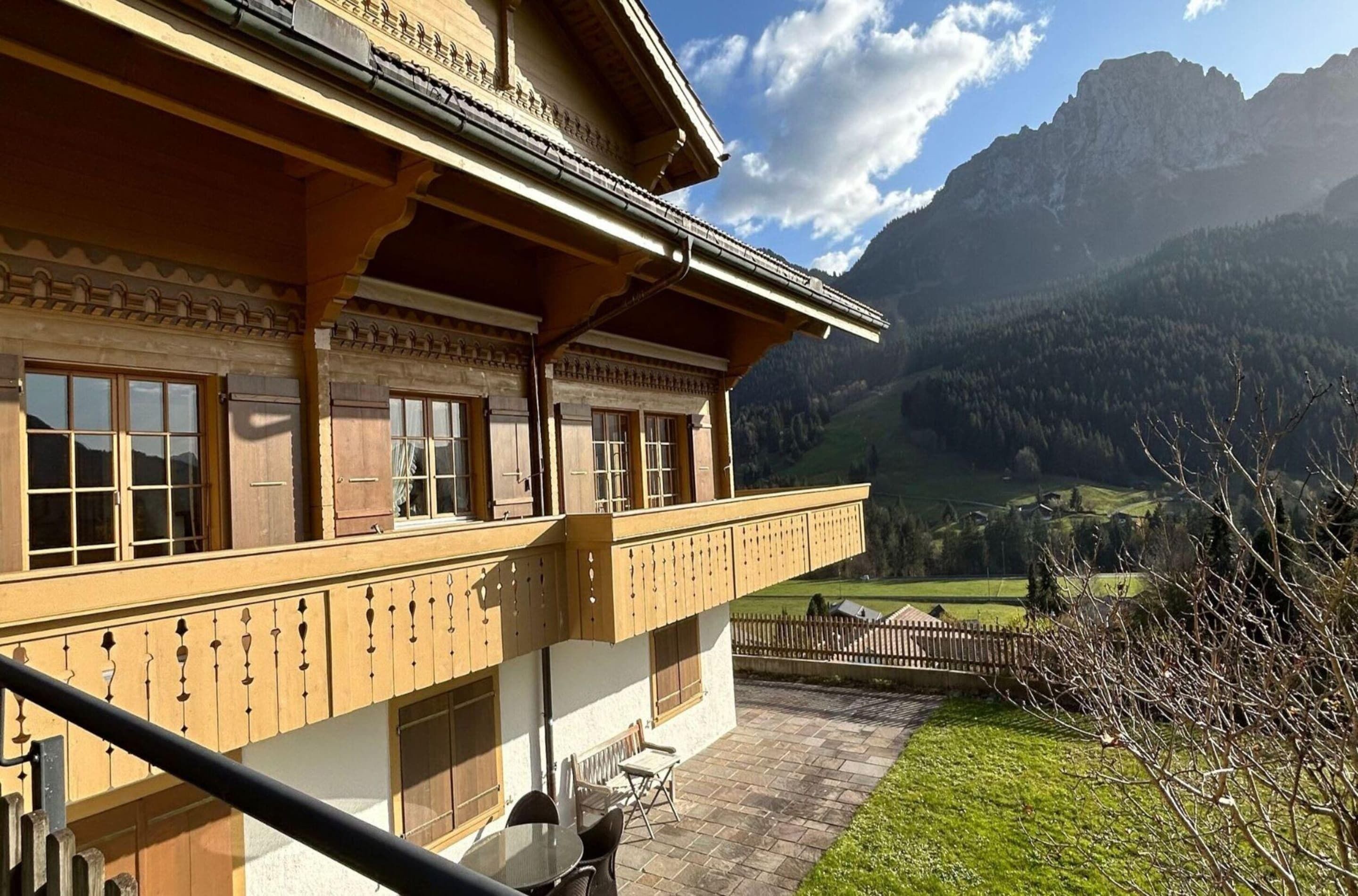 A traditional chalet with a balcony overlooking a mountainous landscape.