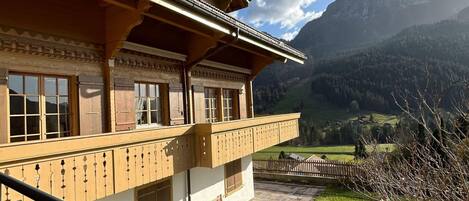 A traditional chalet with a balcony overlooking a mountainous landscape.