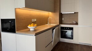Une cuisine moderne équipée d’un four encastré, d’un four à micro-ondes et d’un évier, avec un bol de citrons posé sur le plan de travail.